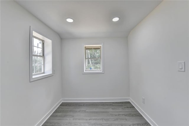 unfurnished room featuring baseboards, a wealth of natural light, and wood finished floors
