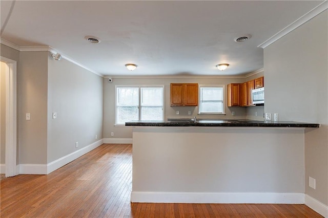 kitchen featuring crown molding, kitchen peninsula, and light hardwood / wood-style flooring