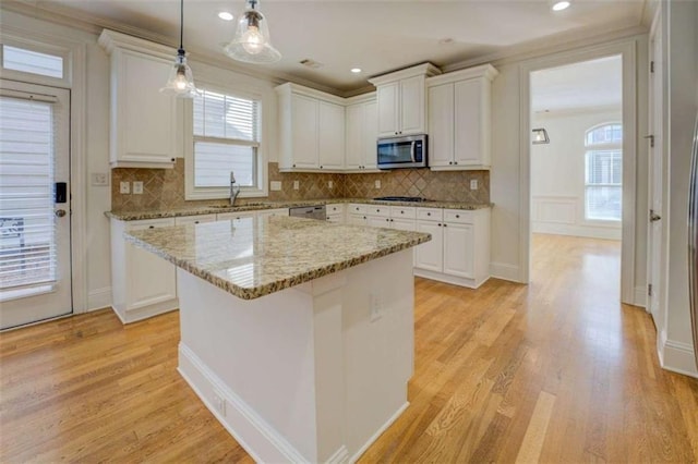 kitchen with a kitchen island, sink, white cabinets, light stone counters, and stainless steel appliances