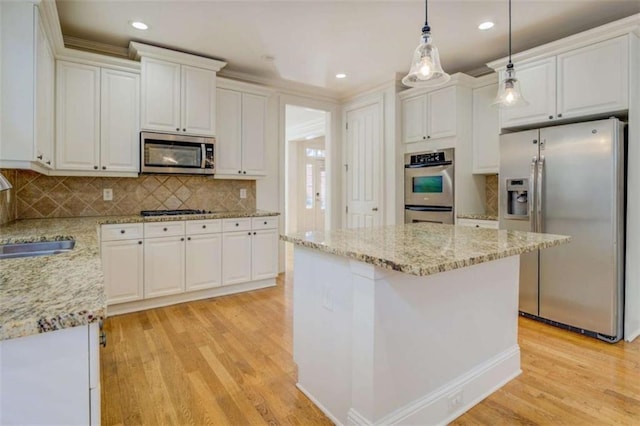 kitchen featuring white cabinetry, sink, decorative light fixtures, and appliances with stainless steel finishes