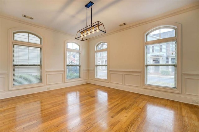 unfurnished dining area with ornamental molding, a notable chandelier, and light wood-type flooring