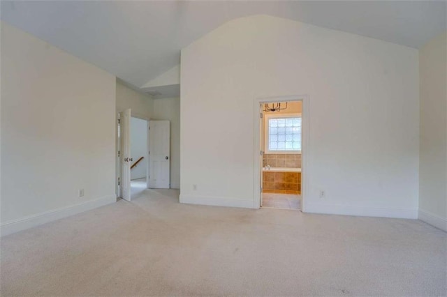 spare room featuring light carpet and vaulted ceiling