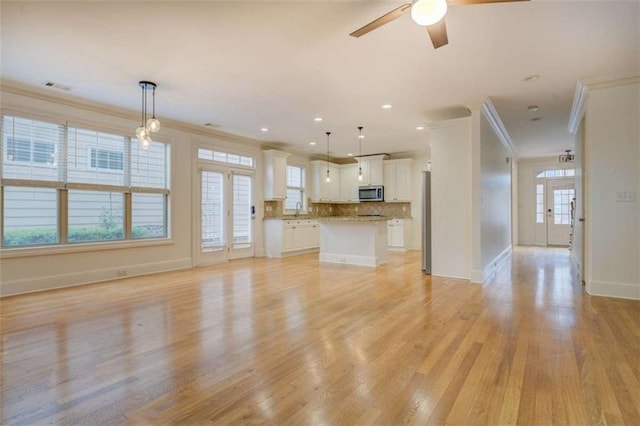 unfurnished living room featuring ornamental molding, sink, ceiling fan, and light hardwood / wood-style floors