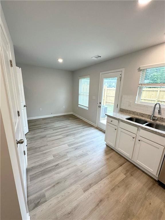 kitchen with decorative backsplash, sink, white cabinets, and light hardwood / wood-style flooring