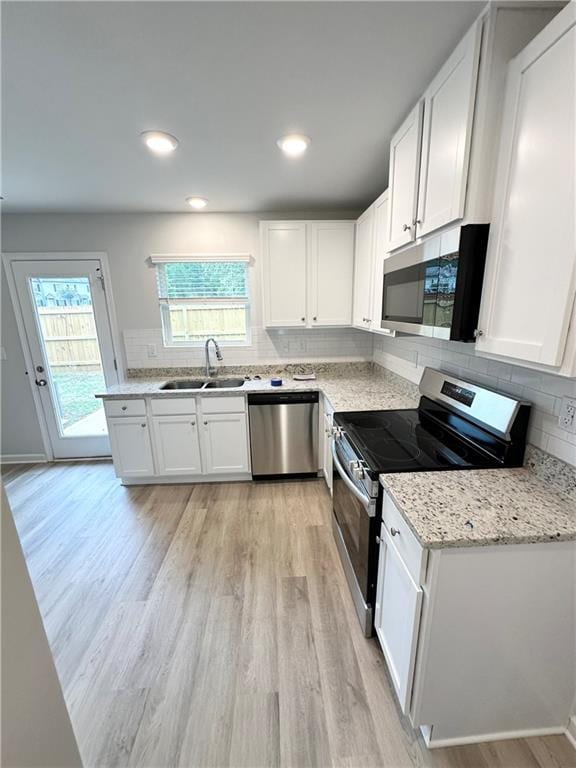 kitchen featuring sink, white cabinetry, tasteful backsplash, light hardwood / wood-style flooring, and appliances with stainless steel finishes