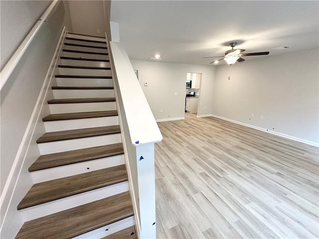 stairs with hardwood / wood-style floors and ceiling fan