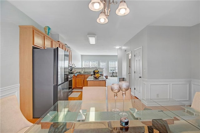 kitchen with wainscoting, a center island, stainless steel appliances, a chandelier, and a decorative wall