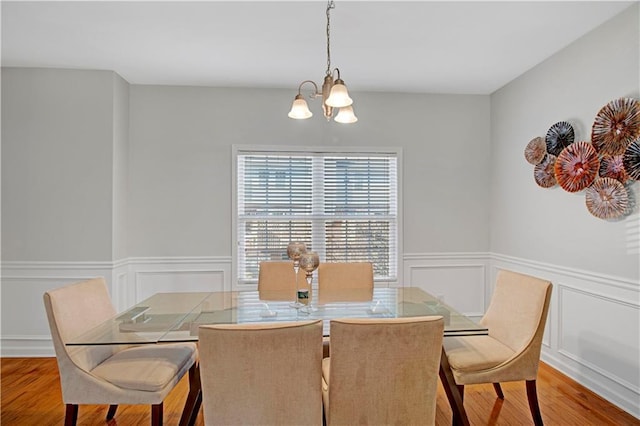 dining room featuring a chandelier, a wainscoted wall, and wood finished floors