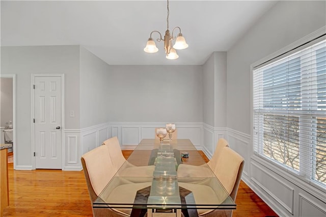 dining space featuring a chandelier, a wainscoted wall, a decorative wall, and light wood finished floors