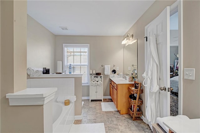 bathroom with vanity, a garden tub, visible vents, and baseboards