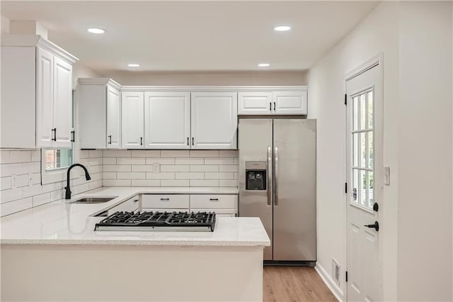 kitchen with decorative backsplash, white cabinetry, sink, and stainless steel appliances