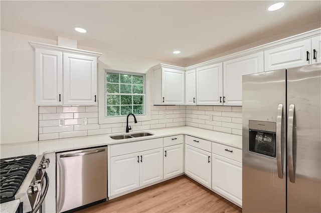 kitchen with decorative backsplash, white cabinetry, sink, and appliances with stainless steel finishes