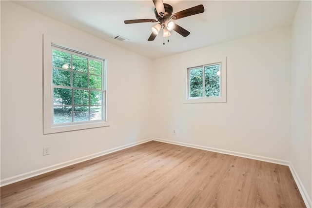 empty room featuring ceiling fan, a wealth of natural light, and light hardwood / wood-style flooring