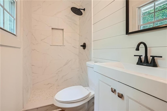 bathroom featuring toilet, vanity, and tiled shower