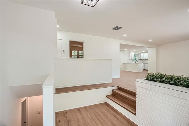 stairs featuring sink and wood-type flooring