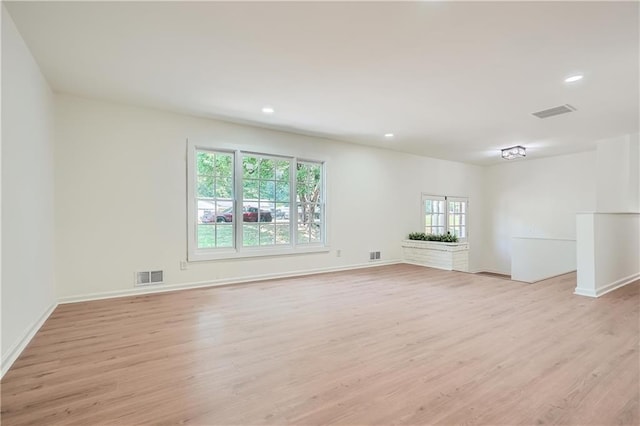 spare room with a fireplace and light hardwood / wood-style flooring