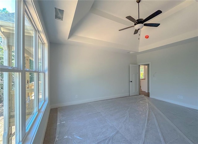 unfurnished room featuring a raised ceiling and ceiling fan