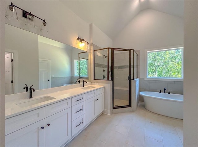 bathroom featuring vanity, vaulted ceiling, a wealth of natural light, and independent shower and bath