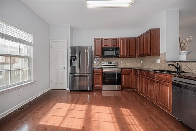 kitchen featuring sink, stainless steel appliances, dark wood-type flooring, and a wealth of natural light