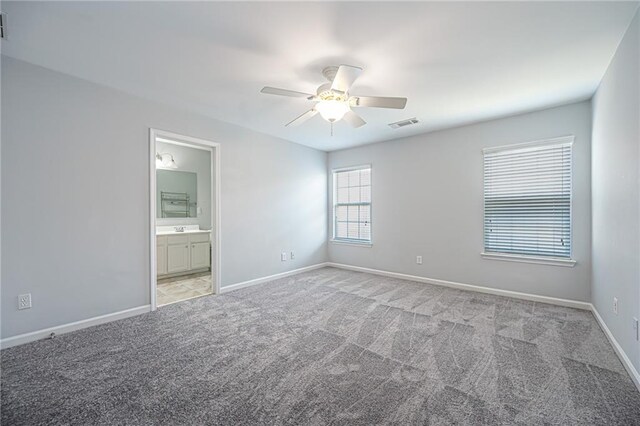 interior space with ceiling fan, light carpet, and ensuite bathroom