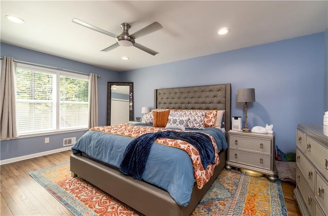 bedroom with wood finished floors, visible vents, a ceiling fan, and baseboards