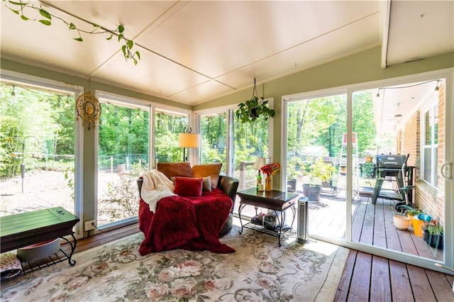 sunroom / solarium featuring vaulted ceiling, hardwood / wood-style flooring, and crown molding