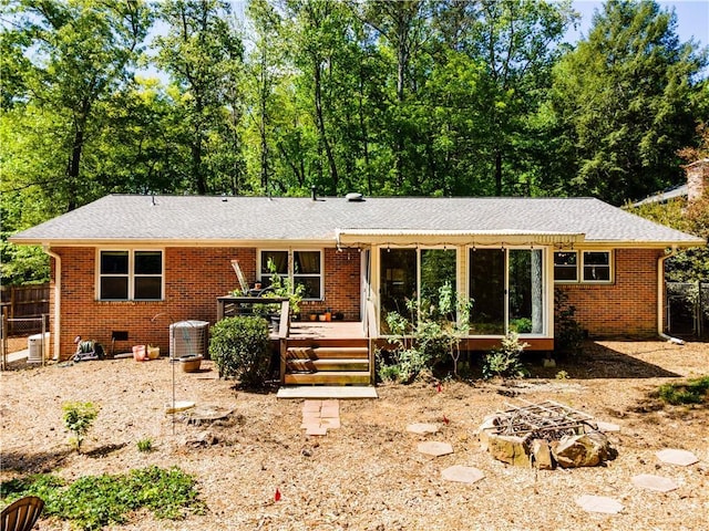 view of front of home featuring brick siding, a wooden deck, fence, and a fire pit