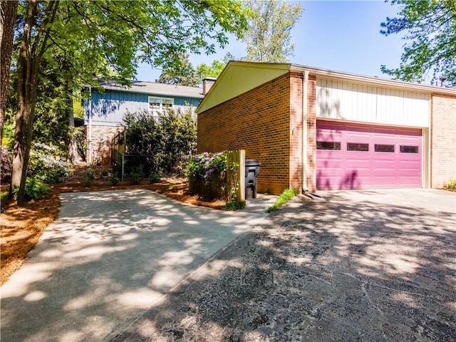 view of side of home with brick siding, driveway, and a garage
