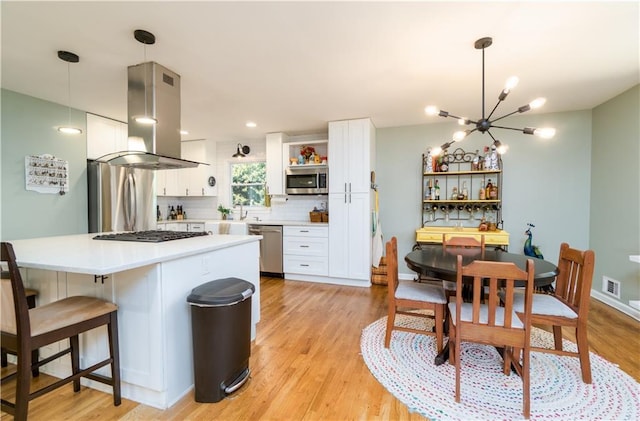 kitchen with open shelves, a chandelier, island exhaust hood, white cabinets, and appliances with stainless steel finishes