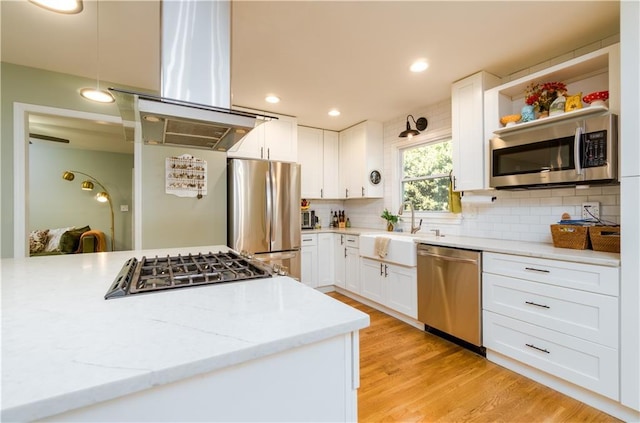 kitchen featuring light stone counters, a sink, white cabinetry, backsplash, and appliances with stainless steel finishes