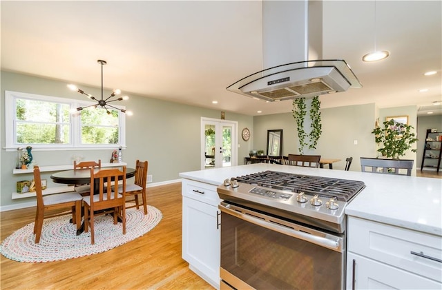 kitchen featuring island range hood, white cabinetry, stainless steel gas range oven, and light countertops