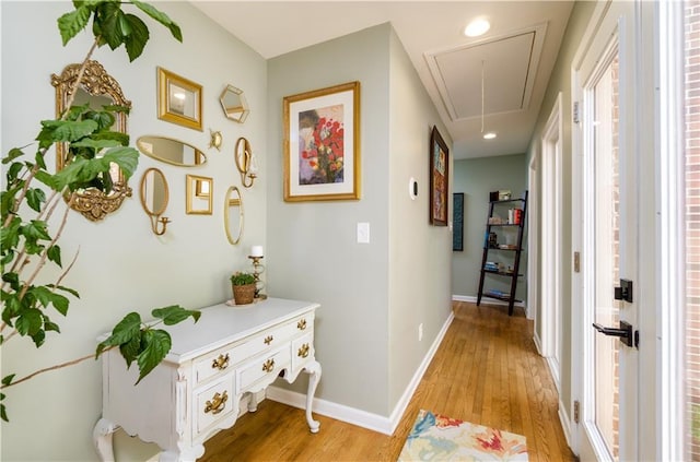 hallway with attic access, light wood-type flooring, baseboards, and recessed lighting
