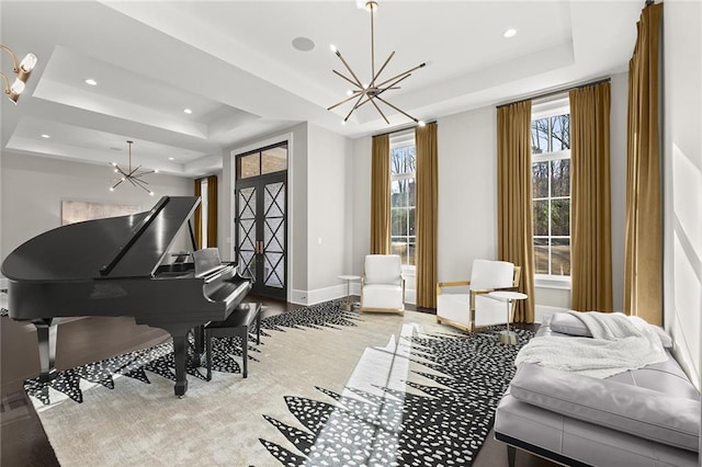 sitting room with a tray ceiling and an inviting chandelier