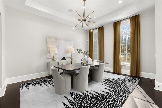 dining area featuring dark hardwood / wood-style flooring, a tray ceiling, and a notable chandelier