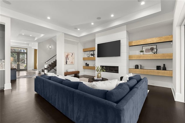 living room with a large fireplace, dark hardwood / wood-style flooring, french doors, and a tray ceiling