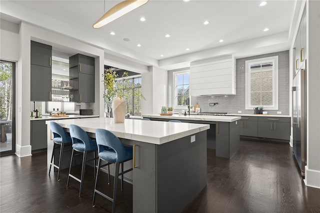 kitchen with a kitchen island, dark hardwood / wood-style flooring, a kitchen breakfast bar, gray cabinetry, and high end fridge