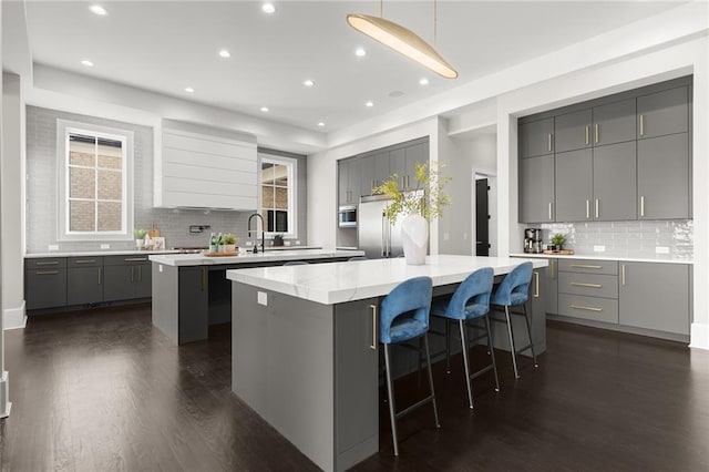 kitchen featuring gray cabinets, a breakfast bar, a center island, and dark hardwood / wood-style flooring