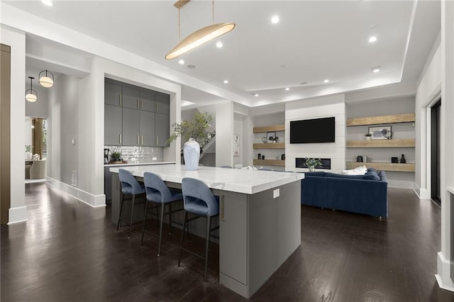 kitchen featuring a large island, gray cabinets, a breakfast bar area, decorative light fixtures, and dark hardwood / wood-style flooring