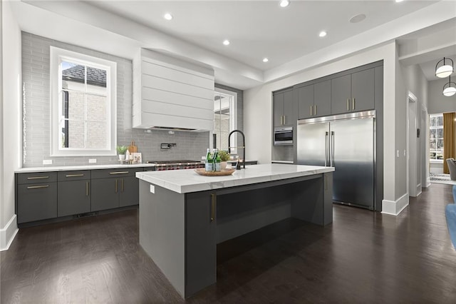 kitchen featuring sink, a kitchen island with sink, gray cabinetry, dark hardwood / wood-style flooring, and built in fridge