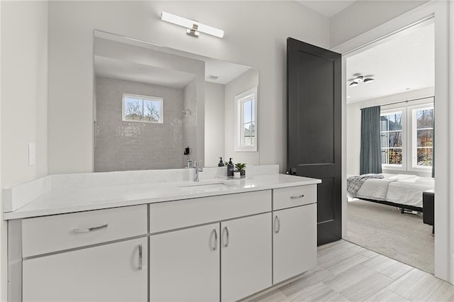 bathroom with ceiling fan, tiled shower, and vanity