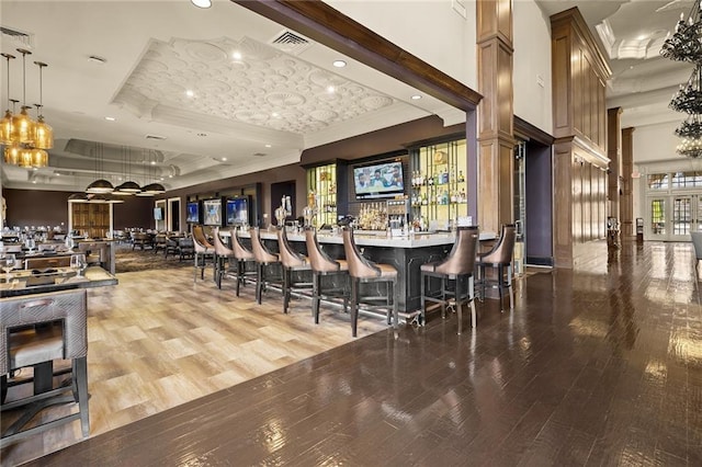 bar featuring hardwood / wood-style flooring, decorative light fixtures, and a raised ceiling