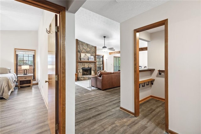 hallway featuring baseboards, a textured ceiling, and wood finished floors