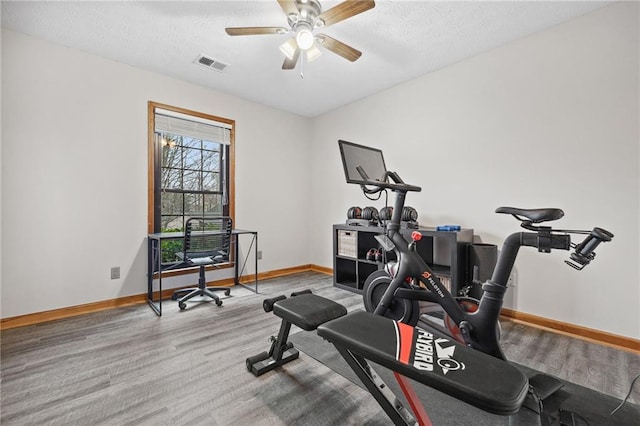 workout area featuring ceiling fan, baseboards, visible vents, and a textured ceiling