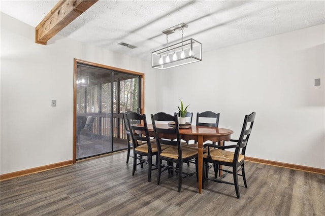 dining room featuring wood finished floors, visible vents, baseboards, beam ceiling, and a textured ceiling