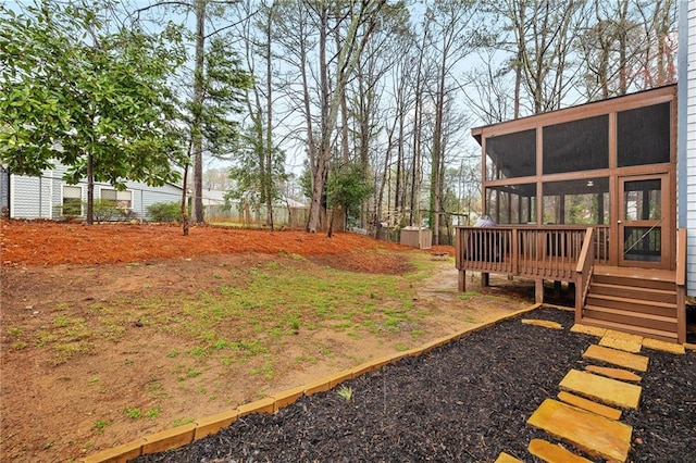 view of yard with fence, a deck, and a sunroom