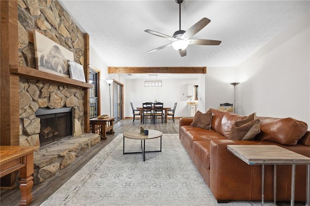 living area with a fireplace, a textured ceiling, a ceiling fan, and wood finished floors