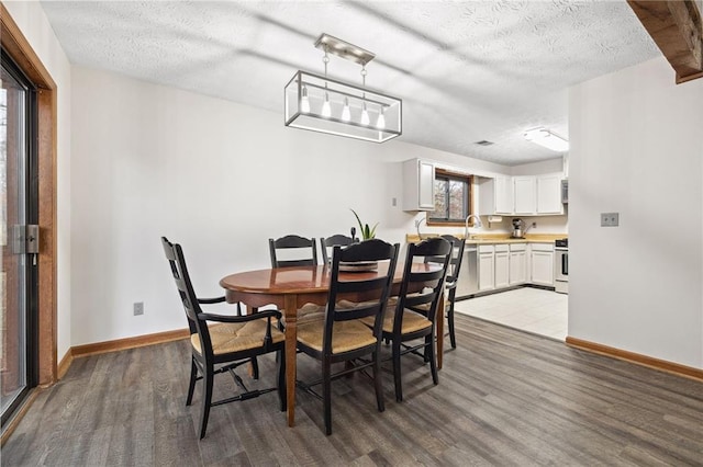 dining room featuring a textured ceiling, baseboards, and wood finished floors