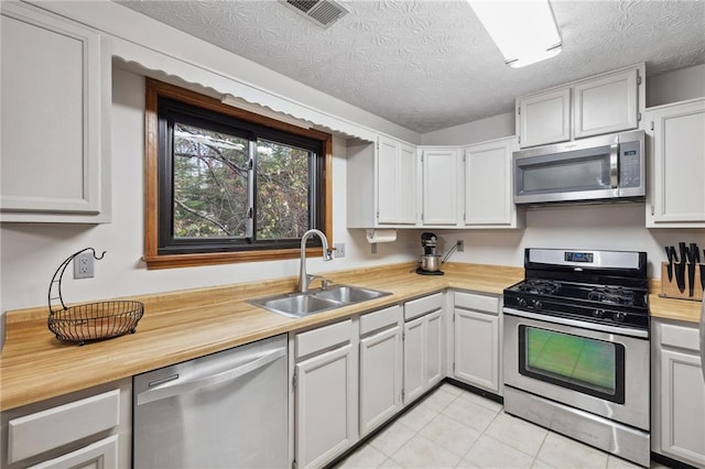 kitchen with visible vents, appliances with stainless steel finishes, light tile patterned flooring, a textured ceiling, and a sink