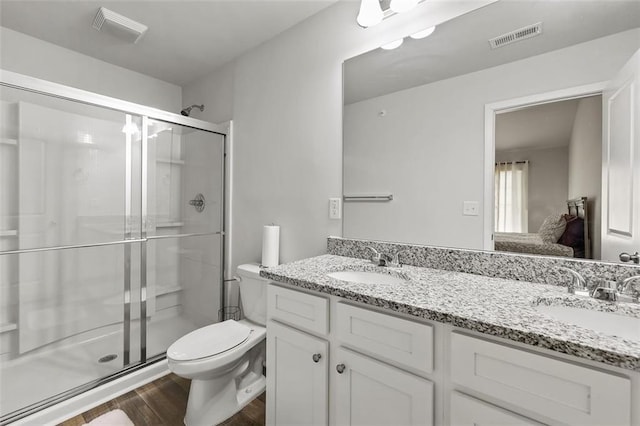 bathroom with hardwood / wood-style flooring, vanity, a shower with shower door, and toilet