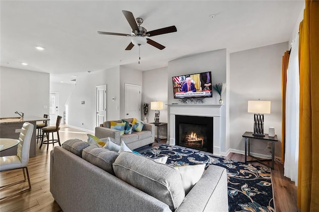 living room featuring ceiling fan, wood-type flooring, and sink